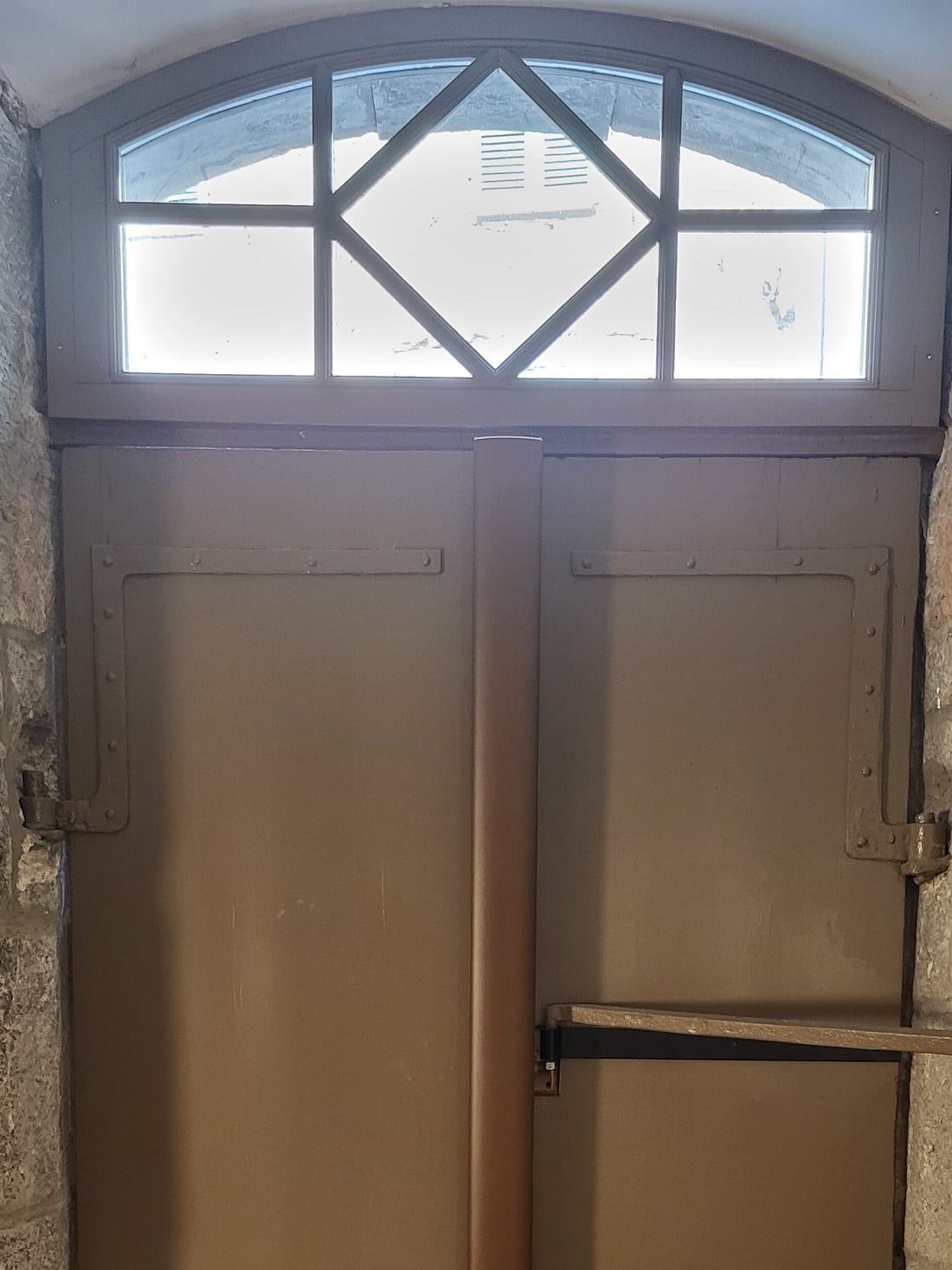 Porte cochère de mas restaurée, vantaux peints gris-taupe à pentures forgées