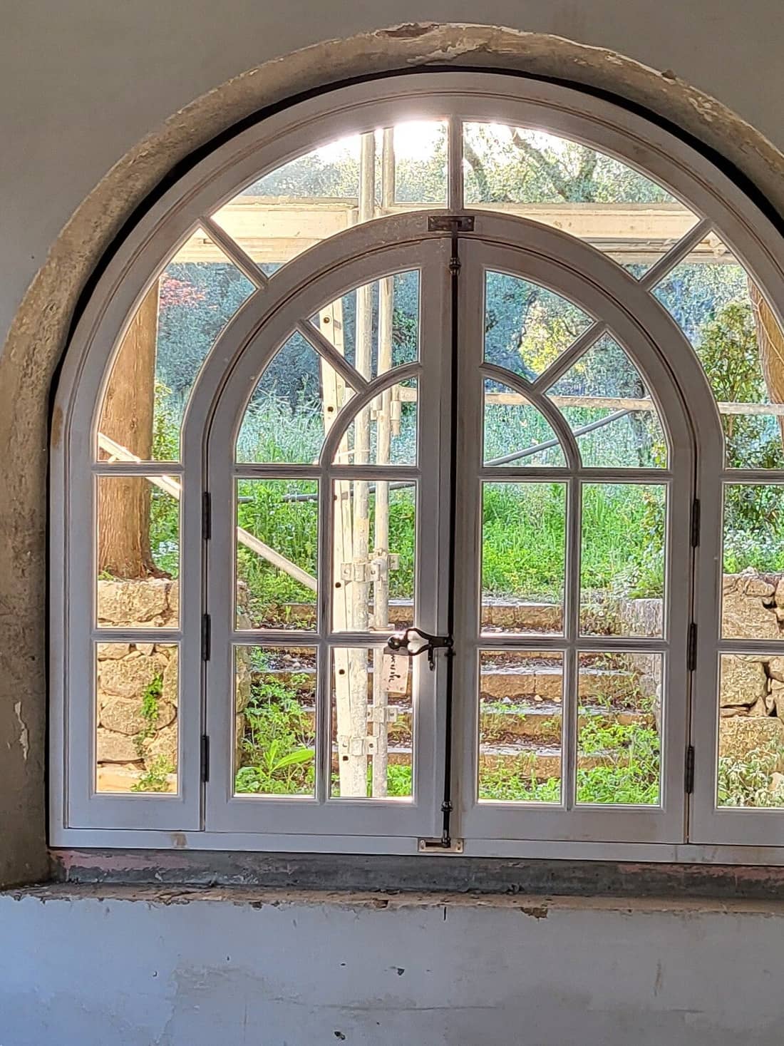 Fenêtre cintrée en bois à petits bois posée dans une niche de pierre