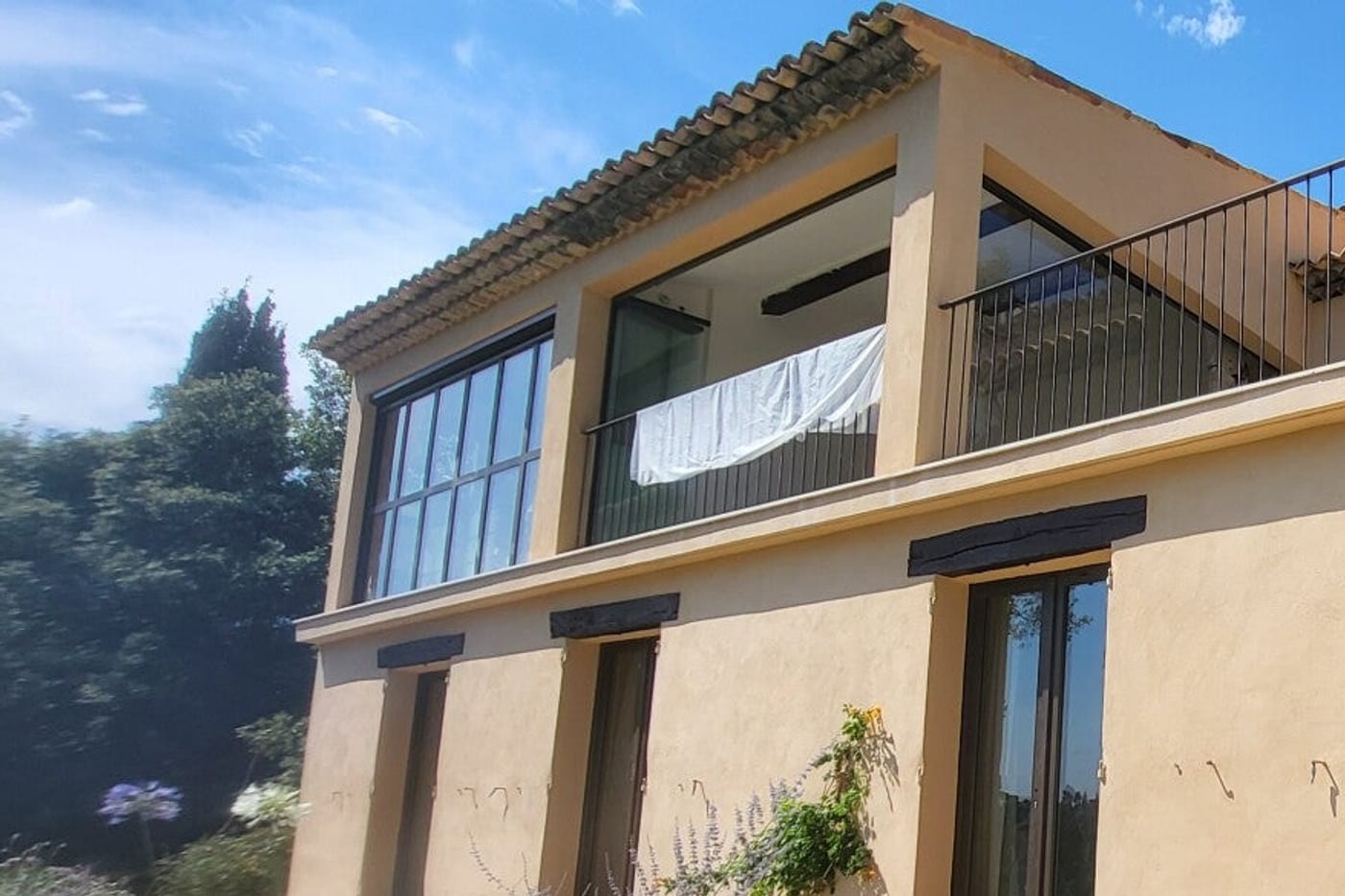 Grandes portes-fenêtres en bois teinté foncé sur une villa provençale enduite ocre